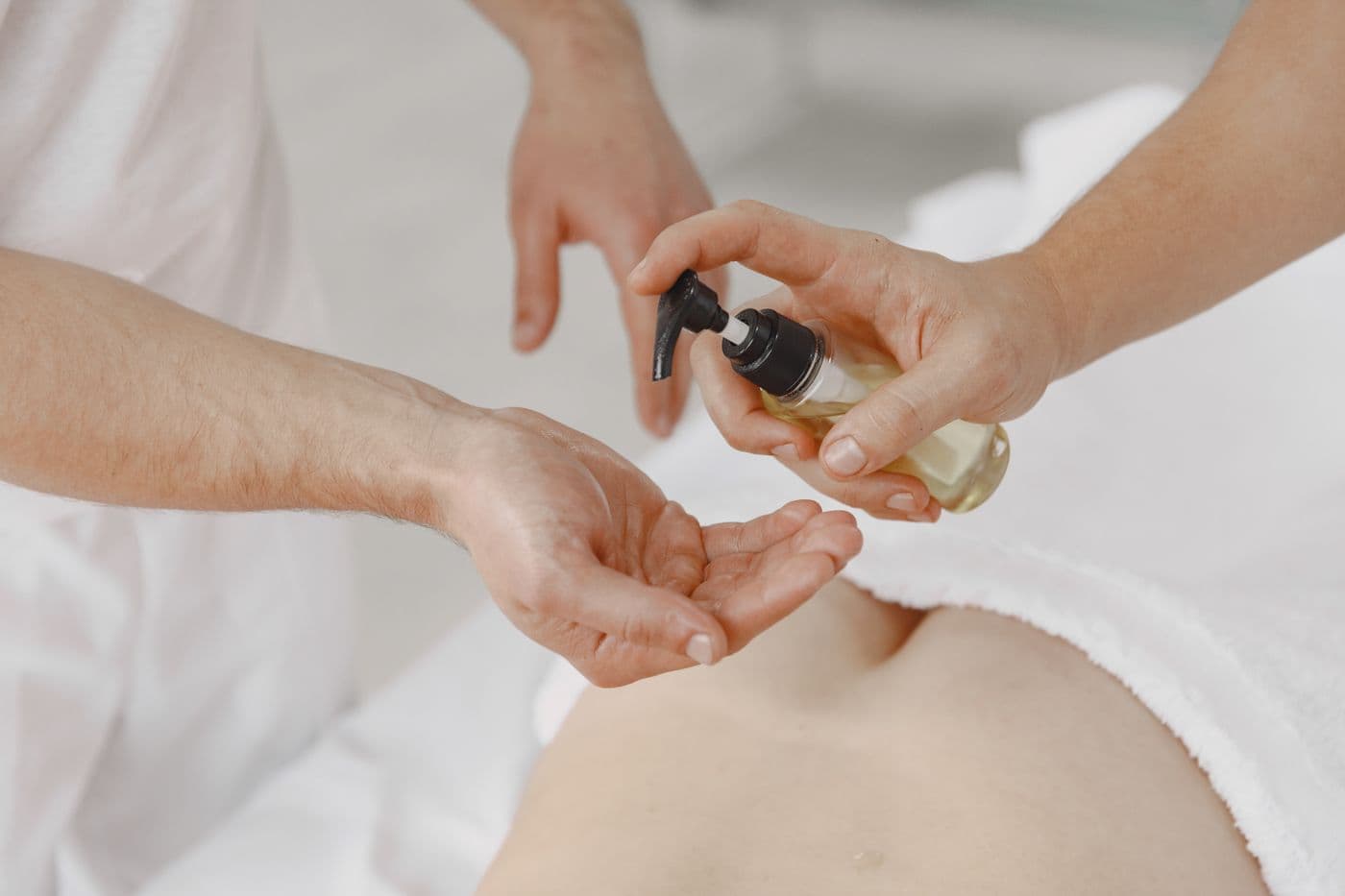 Una terapeuta vierte aceite tibio en sus manos